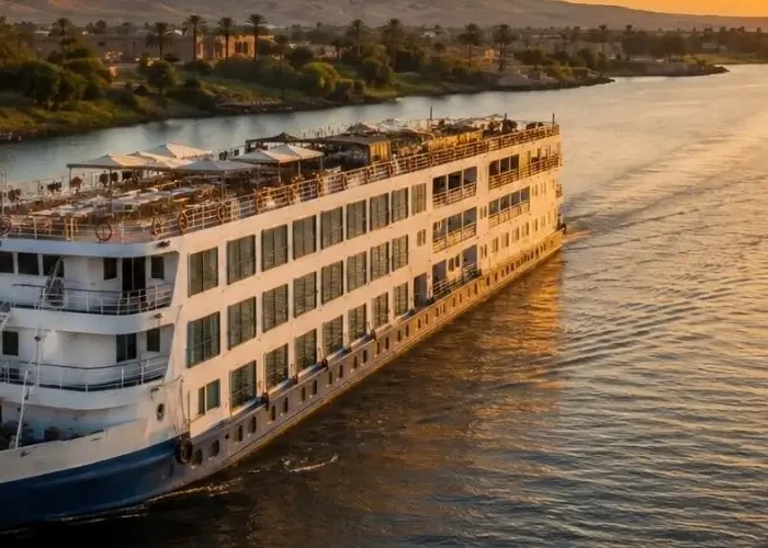 Large multi-deck Nile cruise ship sailing along the river in Egypt at sunset, representing the choice between a classic Nile cruise vs a Dahabiya sailing boat