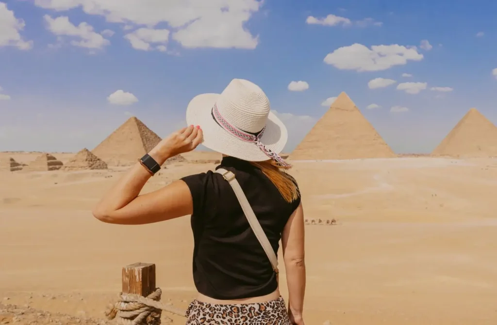Woman wearing a sun hat looking out at the Pyramids of Giza under a clear blue sky during a trip to Egypt in November.